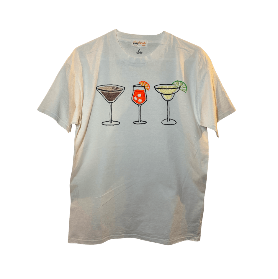 T-shirt oversize blanc, 100% coton. Personnalisation du t-shirt grâce à des broderies. Il faut choisir parmi un choix de broderies dessinées à la main sur le thème de l’été sur la Côte d’Azur dans les Alpes Maritimes, 06. Il faut aussi choisir la position de la broderie entre à gauche côté cœur, à droite ou au milieu. Toutes les broderies sont faites à la commande selon la personnalisation choisie. Ici, il s’agit de la broderie 3 cocktails : espresso martini, Aperol spritz et margarita. 