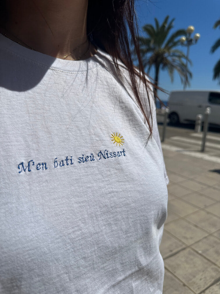 T-shirt oversize blanc, 100% coton. Personnalisation du t-shirt grâce à des broderies. Il faut choisir parmi un choix de broderies dessinées à la main sur le thème de l’été sur la Côte d’Azur dans les Alpes Maritimes, 06. Toutes les broderies sont faites à la commande selon la personnalisation choisie. Ici, il s’agit de la broderie "m'en bati sieu Nissart" pour tous les niçois niçoises Nice