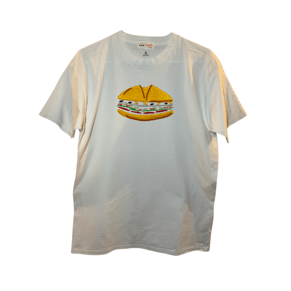 T-shirt oversize blanc, 100% coton. Personnalisation du t-shirt grâce à des broderies. Il faut choisir parmi un choix de broderies dessinées à la main sur le thème de l’été sur la Côte d’Azur dans les Alpes Maritimes, 06. Il faut aussi choisir la position de la broderie entre à gauche côté cœur, à droite ou au milieu. Toutes les broderies sont faites à la commande selon la personnalisation choisie. Ici, il s’agit de la broderie pan bagnat, sandwich spécialité niçoise. Spécialité de la ville de Nice.