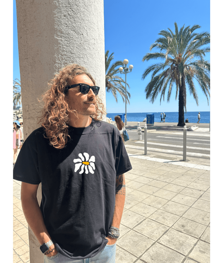 Mannequin, modèle homme t-shirt oversize noir 100% coton avec personnalisation flocage en DTF à l'avant au centre d'une fleur blanche.