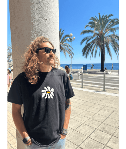 Mannequin, modèle homme t-shirt oversize noir 100% coton avec personnalisation flocage en DTF à l'avant au centre d'une fleur blanche.