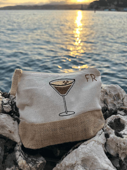 Trousse beige, écru, coton. Personnalisation de la trousse grâce à des broderies et initiales. Il faut choisir parmi un choix de broderies dessinées à la main sur le thème de l’été sur la Côte d’Azur dans les Alpes Maritimes, 06. Initiales brodées sur la trousse en haut à droite. Choix couleur du fil pour les initiales, personnalisation unique. Toutes les broderies sont faites à la commande selon la personnalisation choisie. Ici, il s’agit de la broderie espresso martini. Décor mer, coucher de soleil.