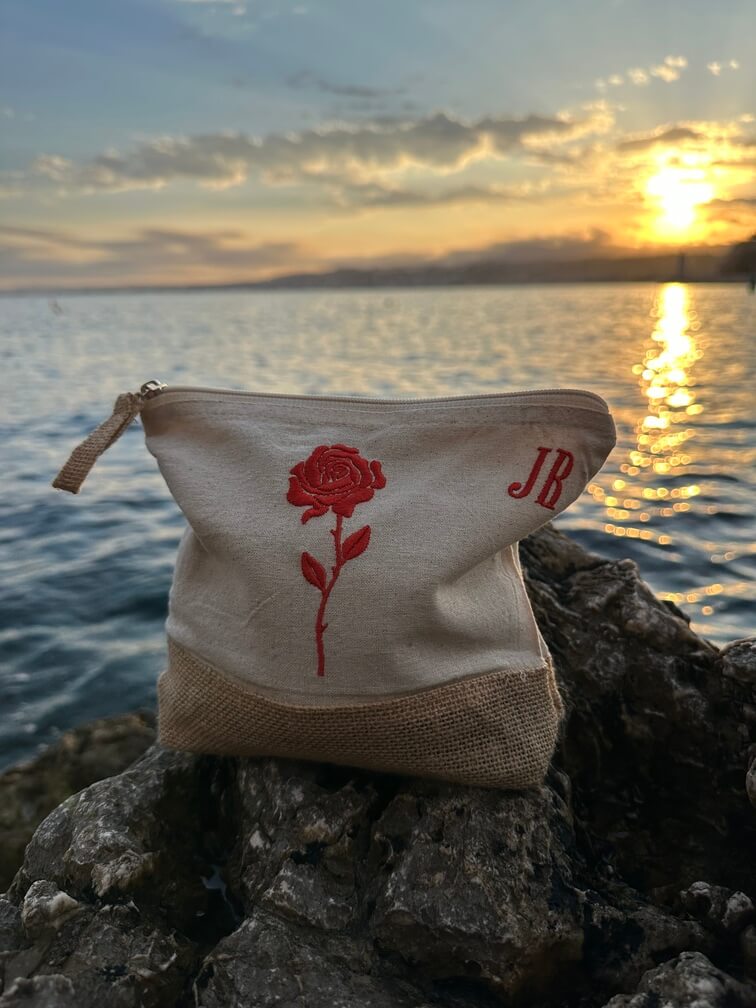 Trousse beige, écru, coton. Personnalisation de la trousse grâce à des broderies et initiales. Il faut choisir parmi un choix de broderies dessinées à la main sur le thème de l’été sur la Côte d’Azur dans les Alpes Maritimes, 06. Initiales brodées sur la trousse en haut à droite. Choix couleur du fil pour les initiales, personnalisation unique. Toutes les broderies sont faites à la commande selon la personnalisation choisie. Ici, il s’agit de la broderie rose rouge.